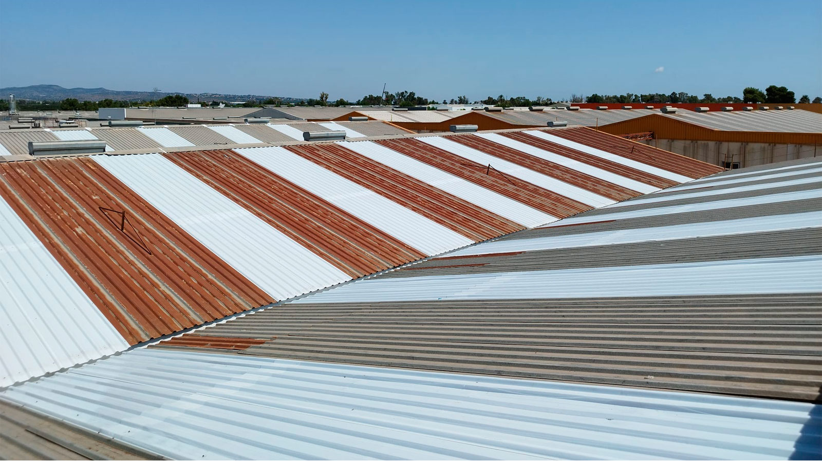 Cubiertas metálicas industriales con impermeabilización blanca aplicada sobre chapa oxidada en nave industrial